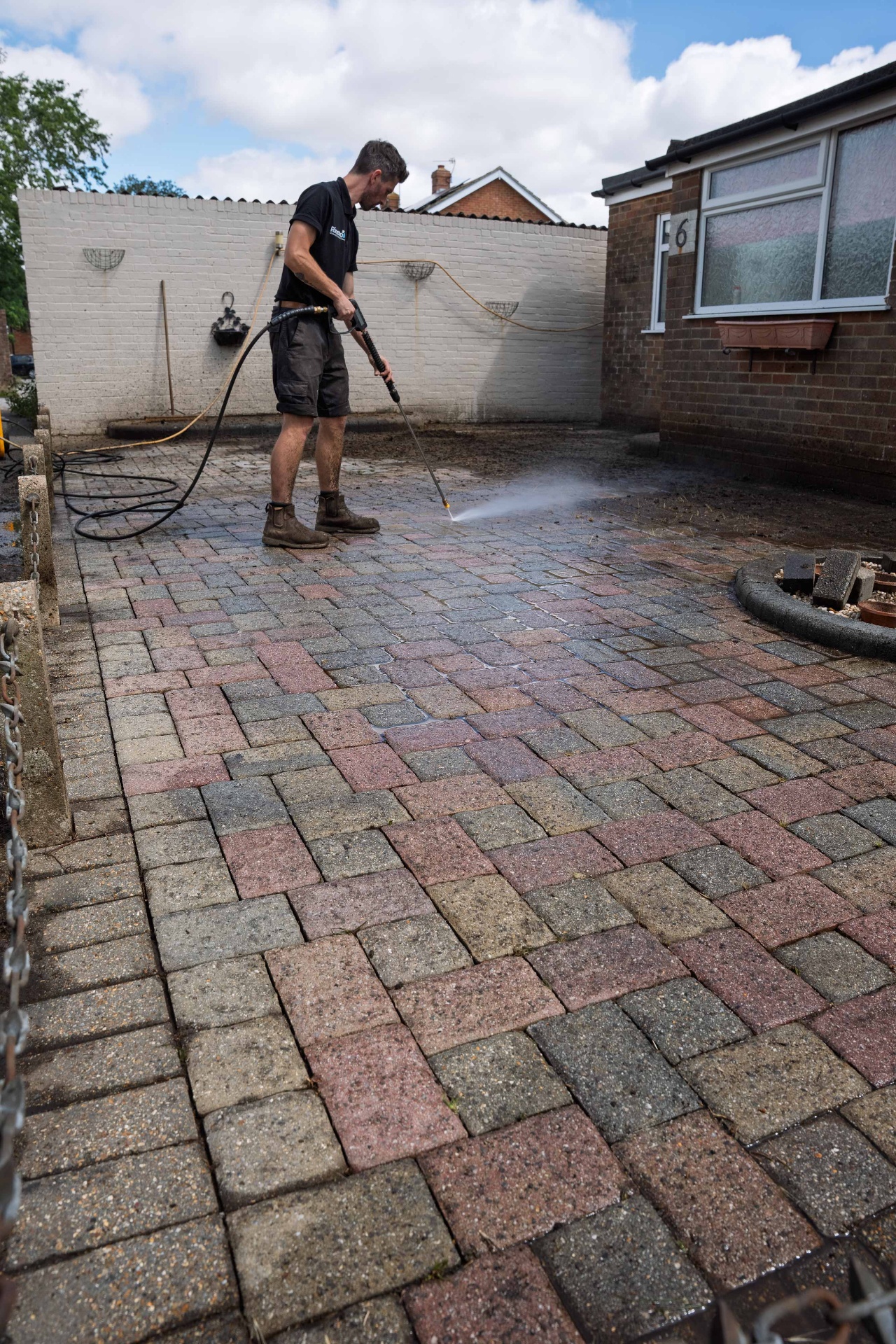 Part-cleaned block paving driveway showing the clean area against the dirty area